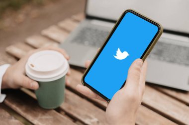 Kahve ve telefonla el sıkışmak, Twitter uygulamasını telefonla ziyaret etmek.