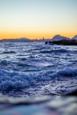 Sahildeki kayaların rengarenk bir günbatımının arkaplanına vurduğu yakın çekim.