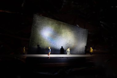 El feneri yansıması olan siyah bir arka planda duran küçük insan figürlerinin yakın çekimi.