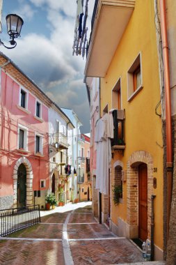 Campobasso, Molise, İtalya 'da bulutlu bir gökyüzünün altındaki binalarla çevrili dikey bir sokak görüntüsü.
