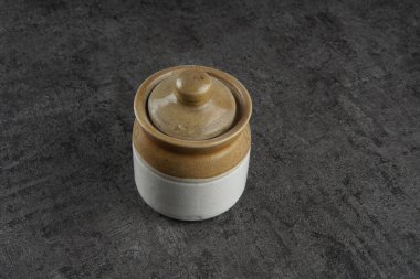 Koyu arkaplanda küçük kahverengi ve beyaz bir şarap kabı.