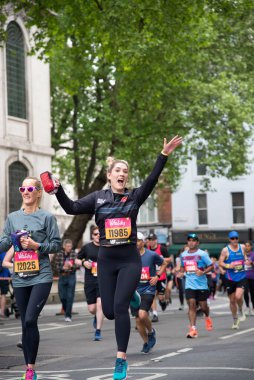 Vitality London 10000 sırasında gülümseyen bir bayan koşucunun dikey çekimi. Londra, İngiltere 'de hayır işleri için çalış.