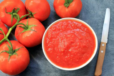 Domates püresi ve gri masada yan yana domatesler.
