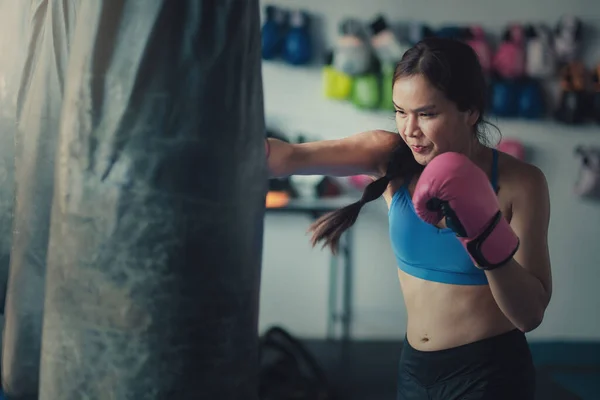 A female boxer hitting a punching bag with boxing gloves at the gym