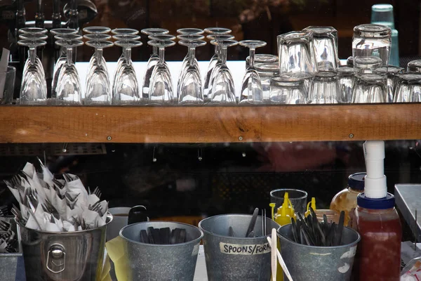 货架上的咖啡厅餐具特写 玻璃杯 金属桶里的叉 — 图库照片