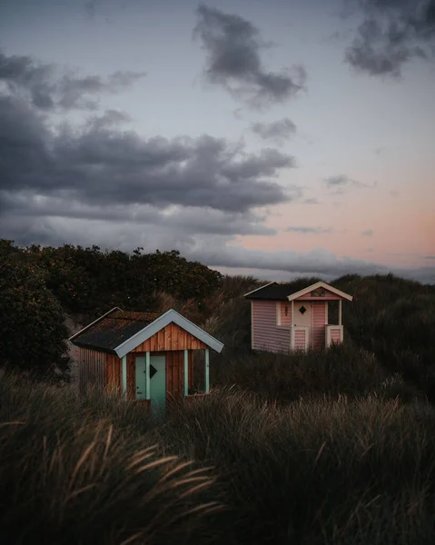 A vertical shot of small colorful cabins in the field during a cloudy day in Skanor, Sweden