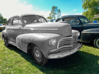 Chascomus, Arjantin - 2009, 2022: Eski kırmızı, boyanmamış Chevrolet Chevrolet Fleetmaster spor coupe 1946 tarafından çimlerin üzerine park edilmiş. Klasik araba şovu..