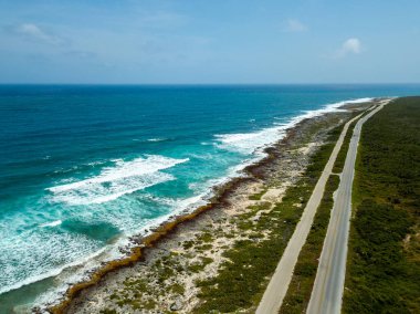 Güneşli bir günde mavi gökyüzüne karşı yeşil vadi ve turkuaz okyanus kıyısının havadan görünüşü.