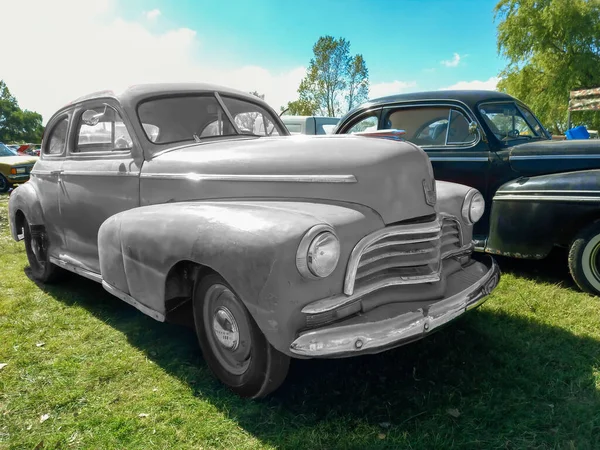 Chascomus, Arjantin - 2009, 2022: Eski kırmızı, boyanmamış Chevrolet Chevrolet Fleetmaster spor coupe 1946 tarafından çimlerin üzerine park edilmiş. Klasik araba şovu..