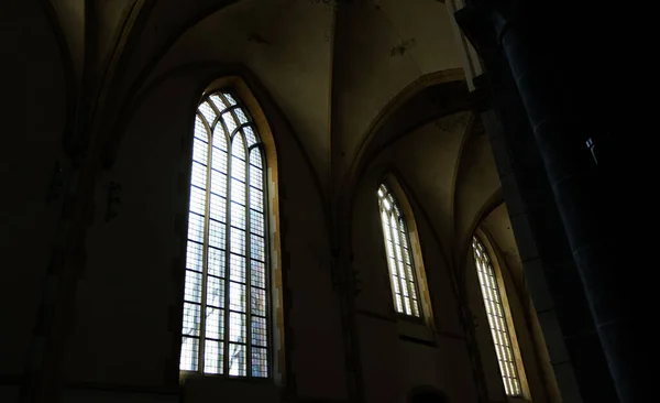 An inside view of a dark hallway of a church with light coming from windows