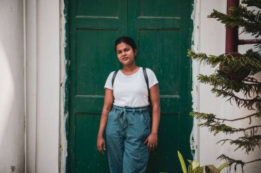 Yeşil kapının yanında poz veren genç bir Hintli kadın.