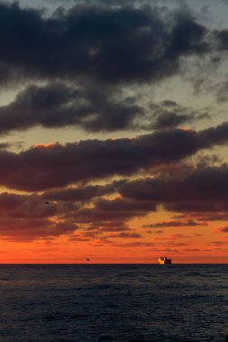 Litvanya 'nın Klaipeda limanında, kayalıklı kırmızı bulutlu gün batımı manzarası