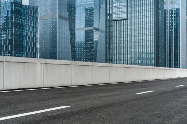 Gündüz vakti şehir merkezinde modern ofis binaları olan boş bir asfalt yola yakın çekim.