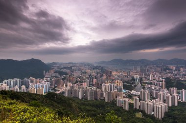 Kowloon şehri, Hong Kong, Çin 'de fırtınalı bulutlu bir gökyüzünün altında Lion Rock tepesinden duvarlarla çevrili.