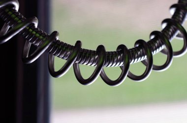 Bulanık bir arkaplanda izole edilmiş siyah, metal bir bobinin yakın plan çekimi.