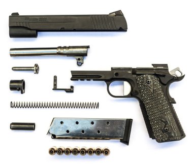 Beyaz arka planda parçalanmış bir tabanca. Ayrı parçalar tabancası. Tabanca Parçası.