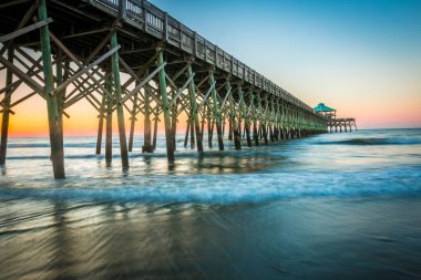 Okyanusun üzerine inşa edilmiş rengarenk günbatımı arka planında bir köprü manzarası.