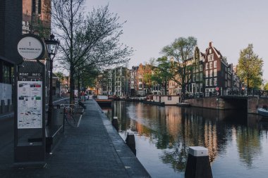 Hollanda, Amsterdam 'da sabah erken saatlerde binalar, sokaklar ve sakin nehir manzarası