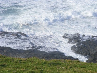 Büyük köpük dalgaları kayalık bir sahile çarpıyor.