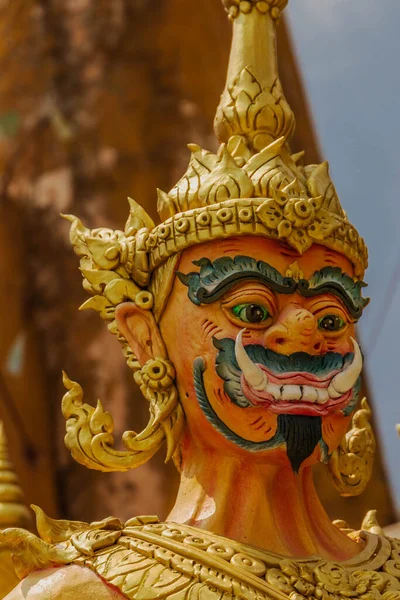 A vertical closeup of a demon statue in a buddhist temple in Thailand.