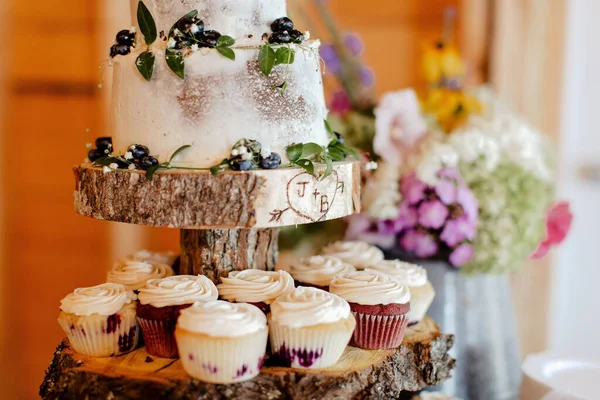 A closeup shot of a wedding cake with cupcakes on wooden boards in New Brunswick, Canada