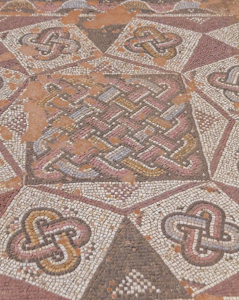 A closeup of a colorful ancient mosaic floor with small colorful stone tiles