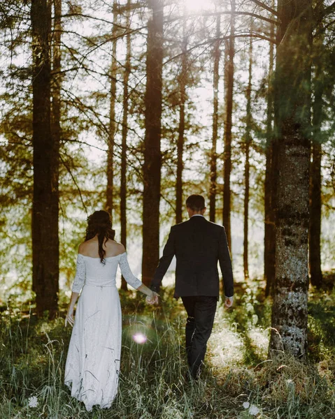A beautiful view of the bride and groom holding hands in the forest