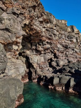 Kayalık adanın dikey görüntüsü ve berrak bir gökyüzü altında sakin bir sahil.