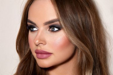 Beyaz bir duvara karşı yumuşak makyajlı güzel sarı saçlı bir kadının beyaz portresi.