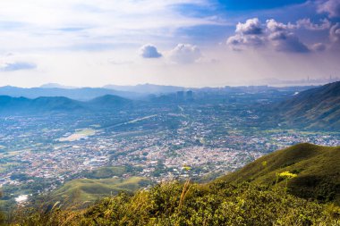 Dağ sıralarının güzel manzarası ve altında bulutlu gökyüzü olan bir kasaba.
