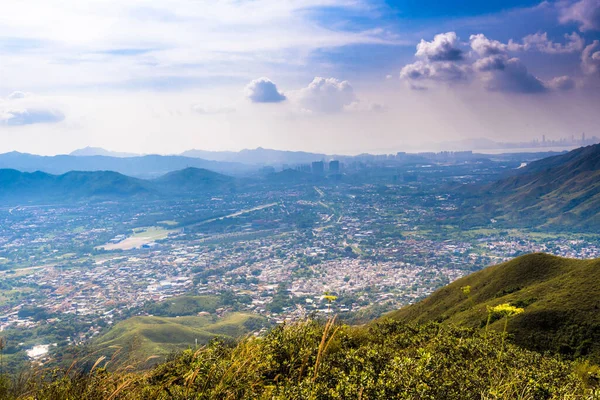 Dağ sıralarının güzel manzarası ve altında bulutlu gökyüzü olan bir kasaba.