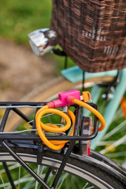 Turuncu çelik kablo kilidi olan bir bisikletin arkası dikey yakın plan.