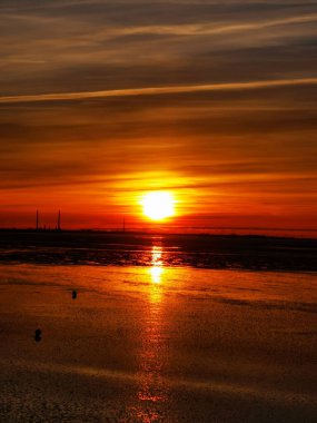 A vertical, breathtaking view of the sunset from a coastline