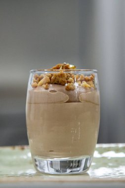 chocolate mousse in a glass with nuts with grain and out of focus