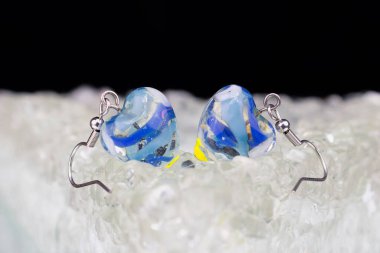 A closeup shot of blue handmade glass heart shaped earrings with blurred background