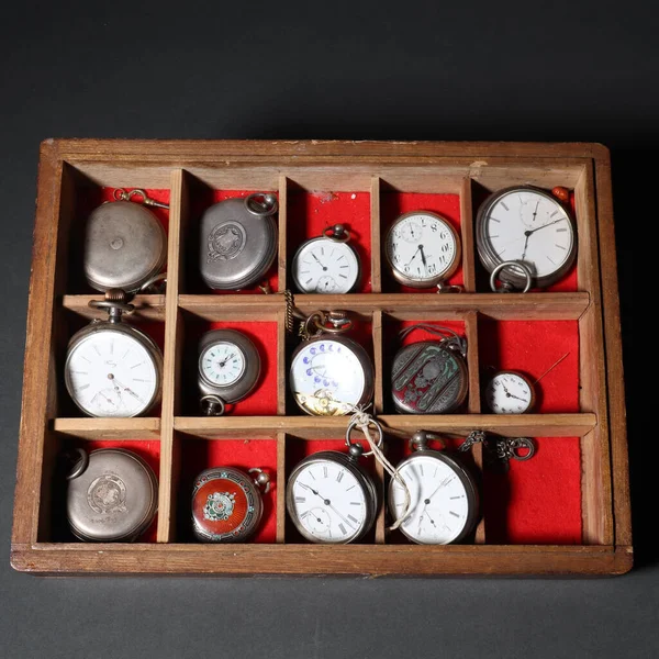 A lot of pocket, antique metal small watches in a special box on a red background