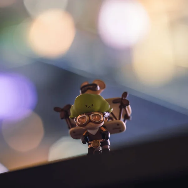 A closeup of a Pop Mart toy figurine of Dimoo preparing to fly isolated on a bokeh background