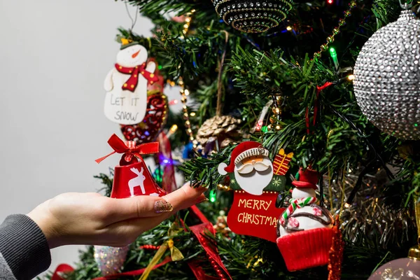 A close-up shot of someone holding a bell decoration of a Christmas tree.