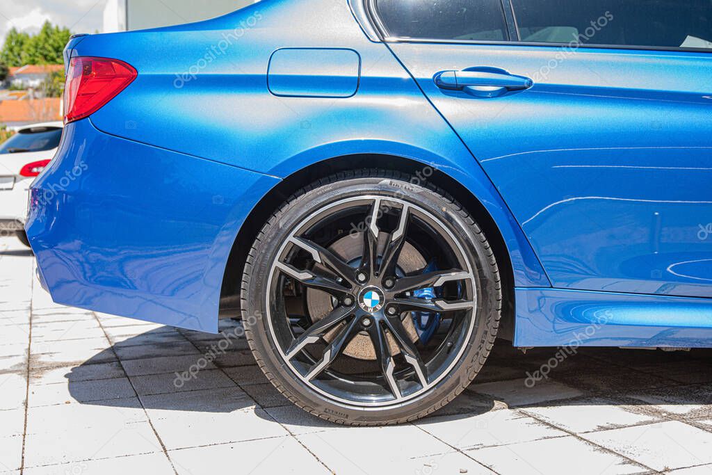 The back side of a Blue BMW M4 Competition Coupe car on a sunny day