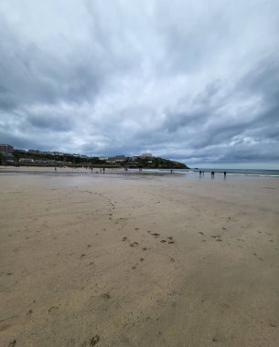 A vertical shot of a gray cloudscape over a sandy beach
