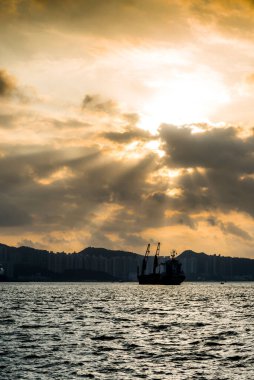 A beautiful vertical view of a boat on a lake with buildings in the background during a scenic sunset