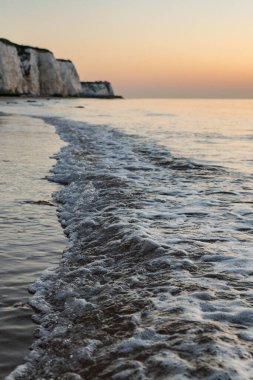 Close up of Waves with Chalk Cliffs in the Background, taken during sunrise.