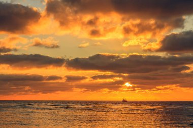A beautiful cloudy sunset with a boat in the distance in the Baltic sea near Klaipeda, Lithuania