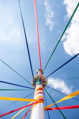 Geleneksel İngiliz Maypole dansı gününde renkli kurdeleli bir direğin alçak açılı çekimi.