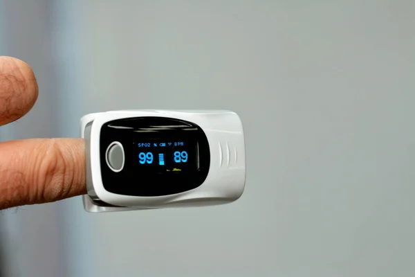 A closeup shot of a fingertip pulse oximeter equipment connected to the index finger of a young man measuring oxygen saturation in blood