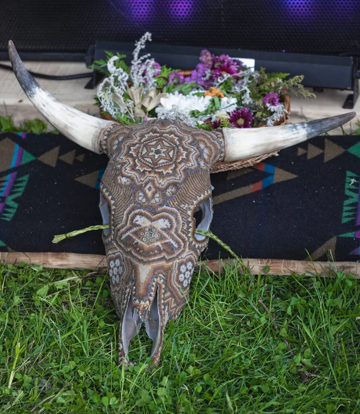 A North American tribal art on a cow skull with flowers and a tribal blanket