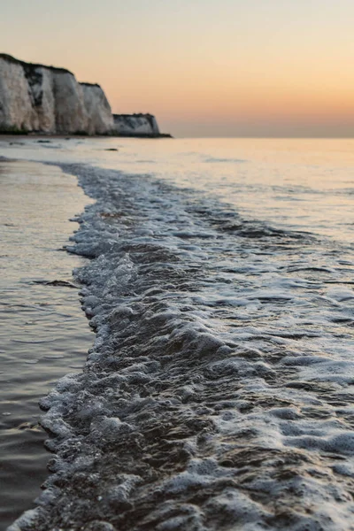 Close up of Waves with Chalk Cliffs in the Background, taken during sunrise.