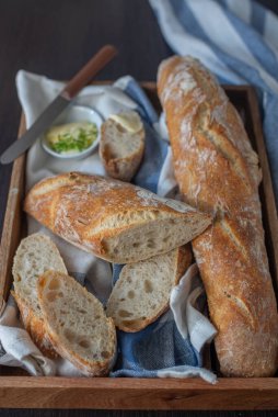 A vertical, top view of a wooden basket full of homemade fresh french Baguette loafs