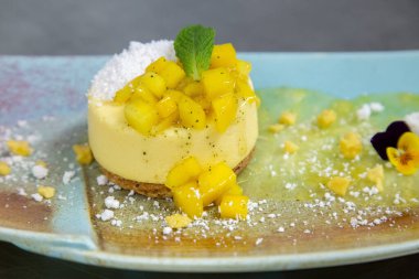 yellow mango mint and edible flowers on cheese cake round
