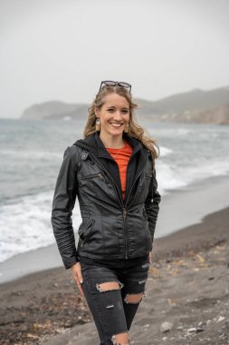 A shallow focus shot of a Caucasian woman smiling on the beach of Santorini, Greece